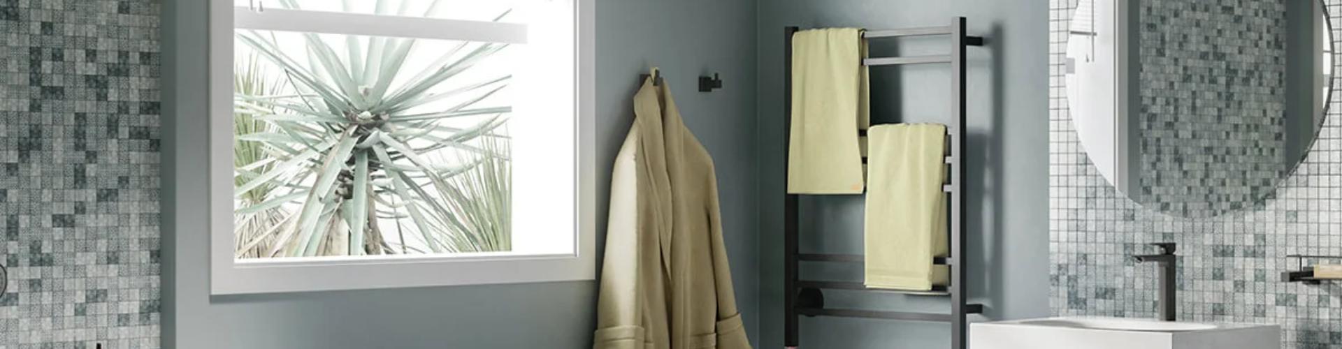 A wall-mounted 8-bar matte black heated towel rack drying muted yellow towels in a bathroom